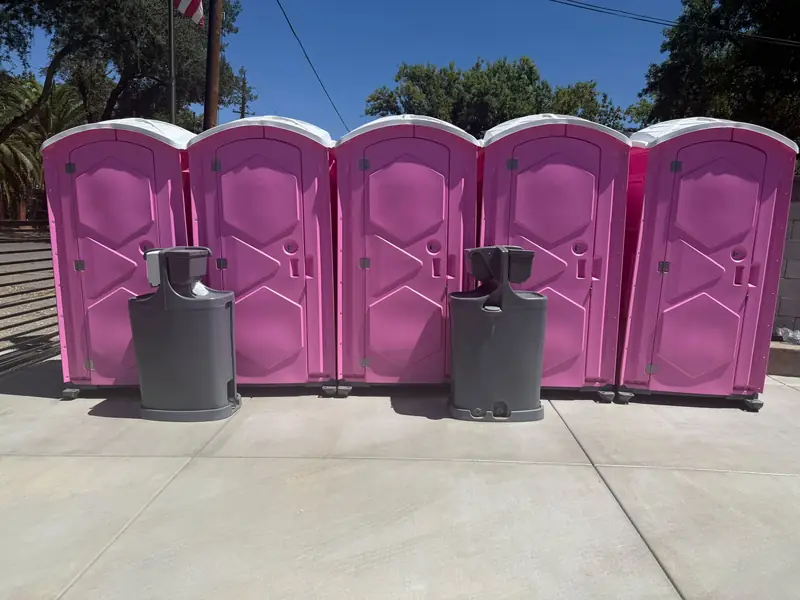 Five pink event portable toilets lined up with two hand washing stations