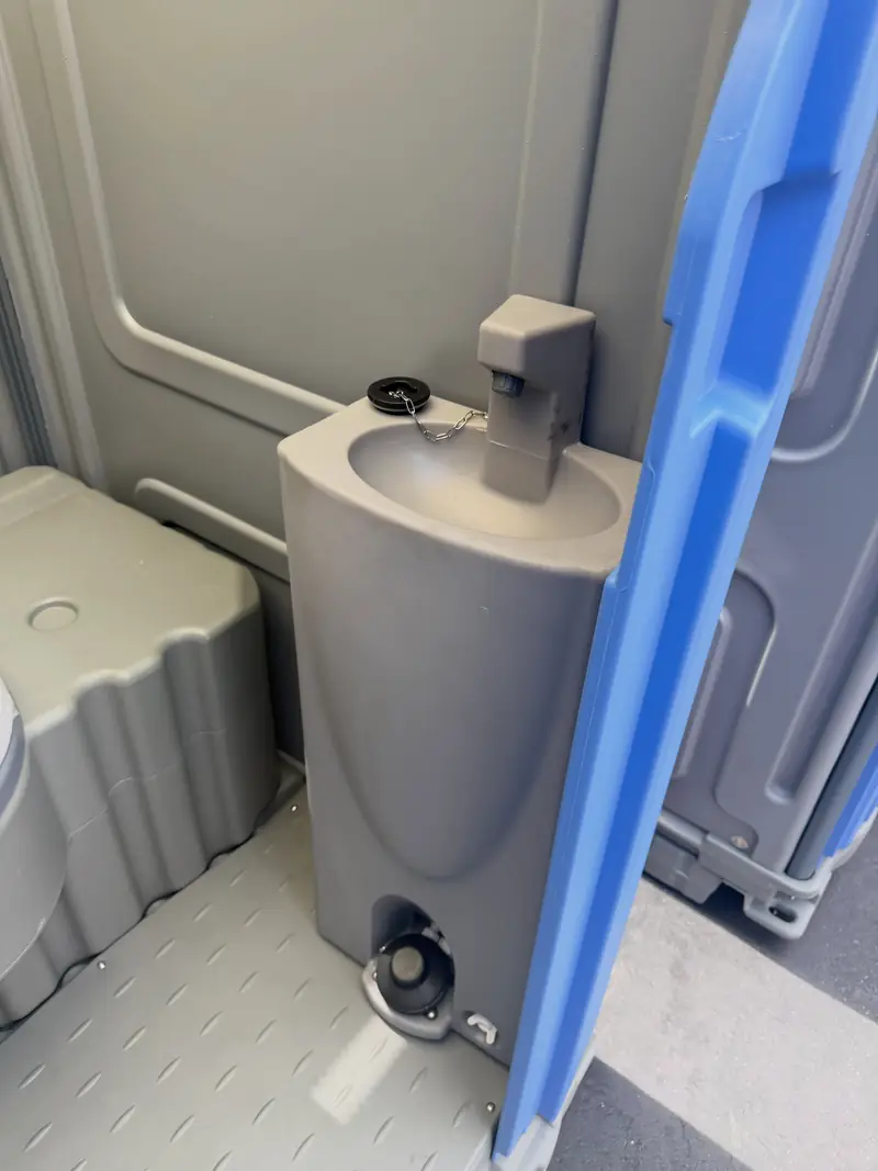 Foot-pump hand sink inside a portable toilet