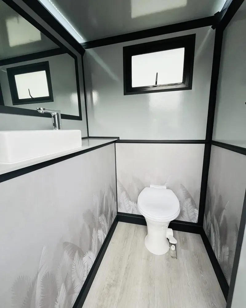 Restroom trailer interior with vanity sink and windows